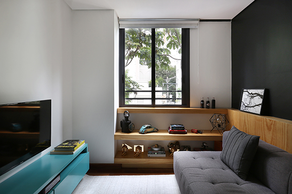 sala de tv com sofá cinza, móvel em pinus e parede pintada de preto
